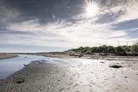 an empty beach with a small body of water near the shore with some rocks in it