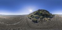 a 360 - view photo of a beach with tire tracks and mountain in the background