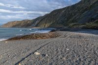 the view of a mountain and a beach from the shoreline of a rocky coastline