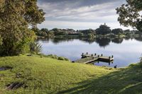 a lake sits behind a grassy hill overlooking the water and trees on either side of it