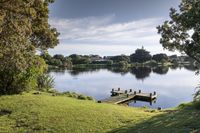 a lake sits behind a grassy hill overlooking the water and trees on either side of it