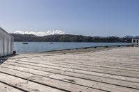 the boardwalk is leading towards the water to a pier next to some boats on the beach