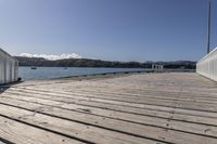 the boardwalk is leading towards the water to a pier next to some boats on the beach