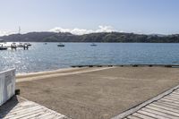 the boardwalk is leading towards the water to a pier next to some boats on the beach