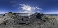 panorama point shot of a view of a rock cliff on the ocean and sky with sun shining