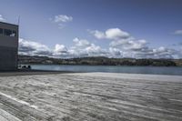 two people sitting on wooden benches by the water on a sunny day by a pier