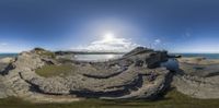 a 360 - view photo of the beach with cliffs and grass near water at low tide