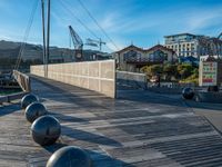 a wooden walkway with metal balls in front of some buildings and buildings and a boat dock