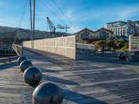 a wooden walkway with metal balls in front of some buildings and buildings and a boat dock