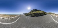 360 panoramic shot of a country road with sun, water and hills in the background