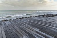 the ocean looks out towards the coast and a wooden boardwalk to its right on the water