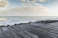 the ocean looks out towards the coast and a wooden boardwalk to its right on the water