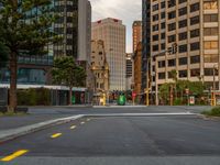 the empty road in front of many large buildings near the street intersection is busy with traffic lights and traffic signals