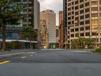 the empty road in front of many large buildings near the street intersection is busy with traffic lights and traffic signals