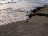 there is a stone that has been washed onto the beach by the ocean and waves