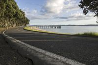 a curved road passes the water towards some land to a bridge and a body of water