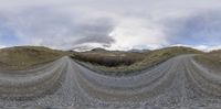 a road with multiple roads in front of mountains and clouds in the distance, taken from a fisheye lens