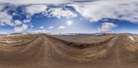 a wide angle view of a dirt track under a partly cloudy sky in an extreme terrain photo