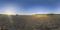 an image of a farm field with some tractor tracks and a sun in the background