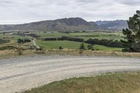 view looking at mountains and a gravel road in the foreground and a hill in the background