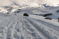 a lone snow skier making his way up a snowy mountain slope with large rocks in the distance