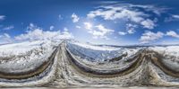 a photo of the sky, clouds, mountains, and snow taken from inside of a fish eye lens