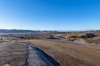 the dirt road has a rock face and snow on top of it in a barren area