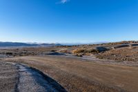 the dirt road has a rock face and snow on top of it in a barren area