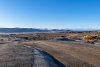 the dirt road has a rock face and snow on top of it in a barren area