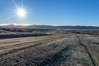 the road in a vast terrain, with mountains and hills in the background with snow on it