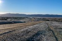 the road in a vast terrain, with mountains and hills in the background with snow on it