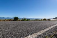 an empty road stretches on the edge of some hills and water is visible in the distance