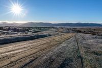 a rural road curves through the middle of a barren landscape, on a sunny day