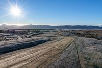 a rural road curves through the middle of a barren landscape, on a sunny day