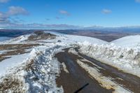 snow on the sides of the road with a mountain in the background under it and blue sky