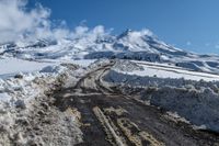 road filled with snow and dust near a mountain on a sunny day in winter season