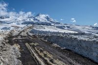 road filled with snow and dust near a mountain on a sunny day in winter season