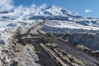 road filled with snow and dust near a mountain on a sunny day in winter season