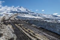 road filled with snow and dust near a mountain on a sunny day in winter season