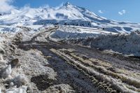 road filled with snow and dust near a mountain on a sunny day in winter season