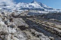 snowy terrain that is mostly covered in snow as part of a road project near some mountains