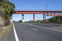 a large bridge on top of an orange bridge over a highway in the middle of nowhere