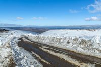 a snowy road with snow on the ground and mountains in the background behind it for a short time