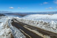 a snowy road with snow on the ground and mountains in the background behind it for a short time