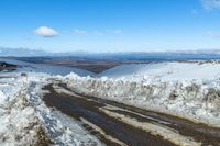 a snowy road with snow on the ground and mountains in the background behind it for a short time