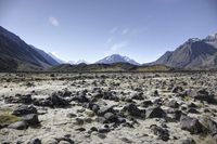 a barren mountain landscape with some rocks in it and the sky above it and some mountains behind