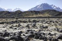 a barren mountain landscape with some rocks in it and the sky above it and some mountains behind