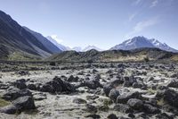 a barren mountain landscape with some rocks in it and the sky above it and some mountains behind