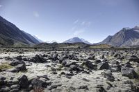 a barren mountain landscape with some rocks in it and the sky above it and some mountains behind