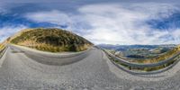 fish - eye view of a road that goes uphill in the background and sky